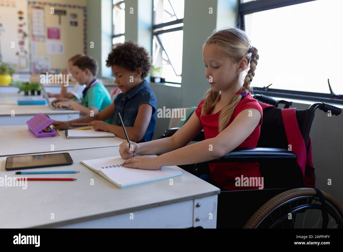 Schoolgirl sitting in a wheelchair in an elementary school classroom