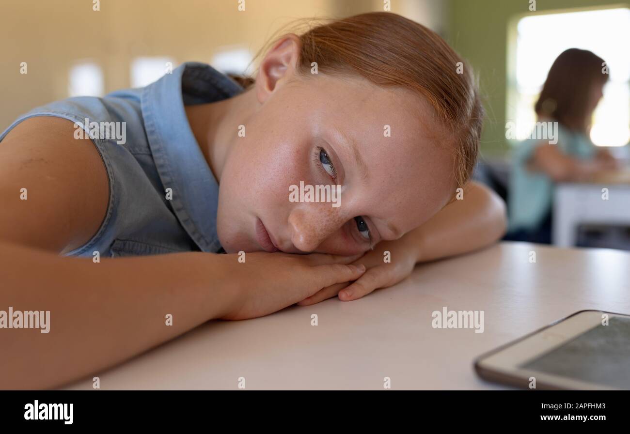 Schoolgirl leaning on her desk in an elementary school classroom Stock Photo
