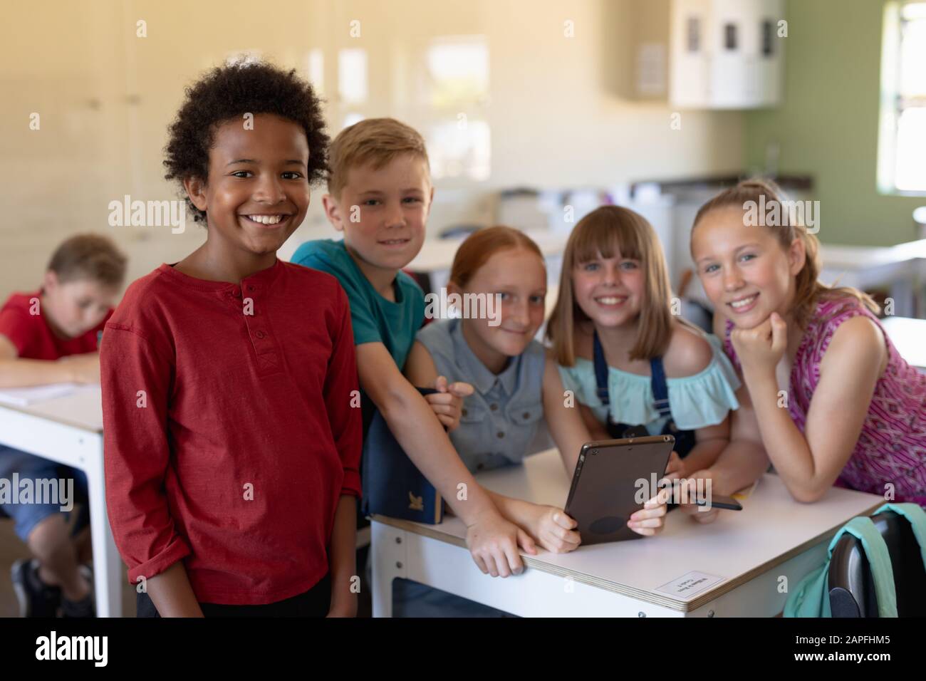 Group of schoolchildren around a desk using a tablet computer Stock Photo