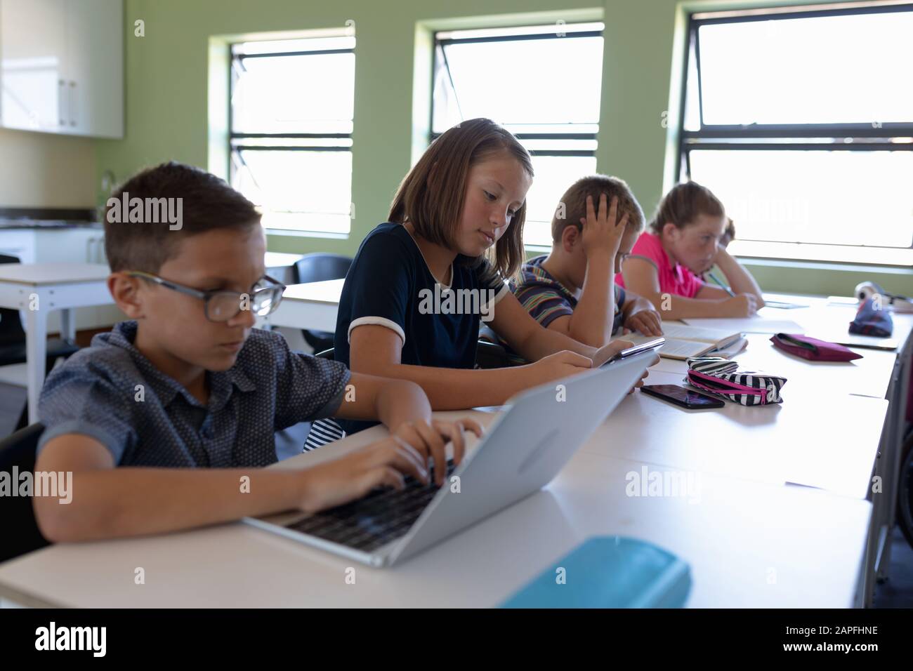 Group of schoolchildren sitting at desks in an elementary school classroom Stock Photo