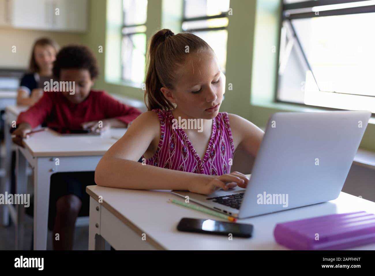 Schoolgirl sitting at a desk using a laptop computer Stock Photo - Alamy