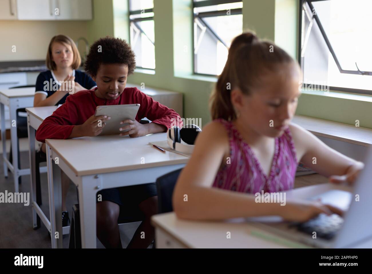 Group schoolchildren sitting at desks using personal computers Stock Photo