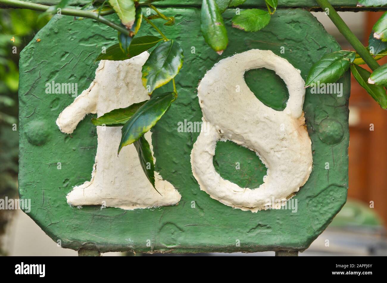 A house number plaque, showing the number eighteen (18) Stock Photo