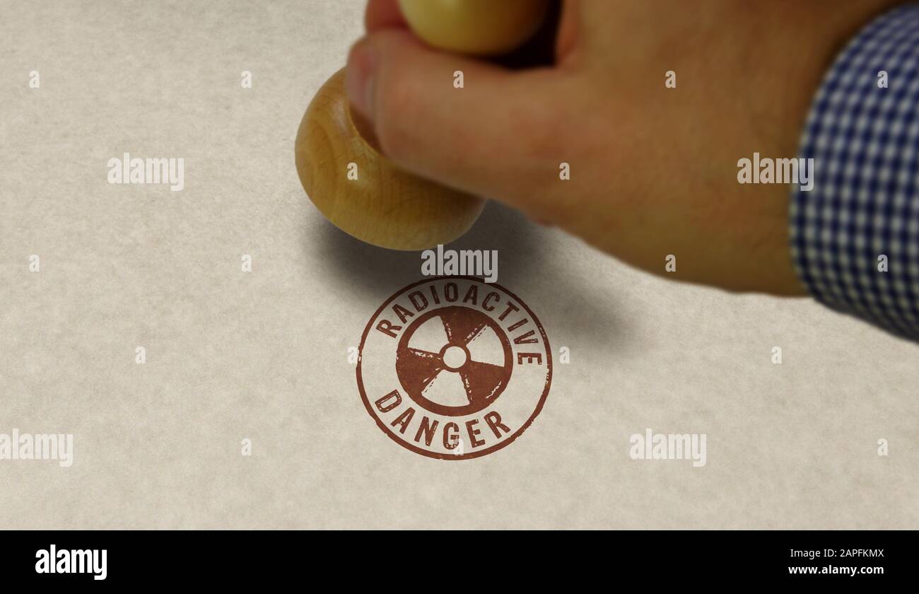 Radioactive danger symbol stamp and stamping hand. Atomic energy warning, radiation alert and nuclear power hazard concept. Stock Photo