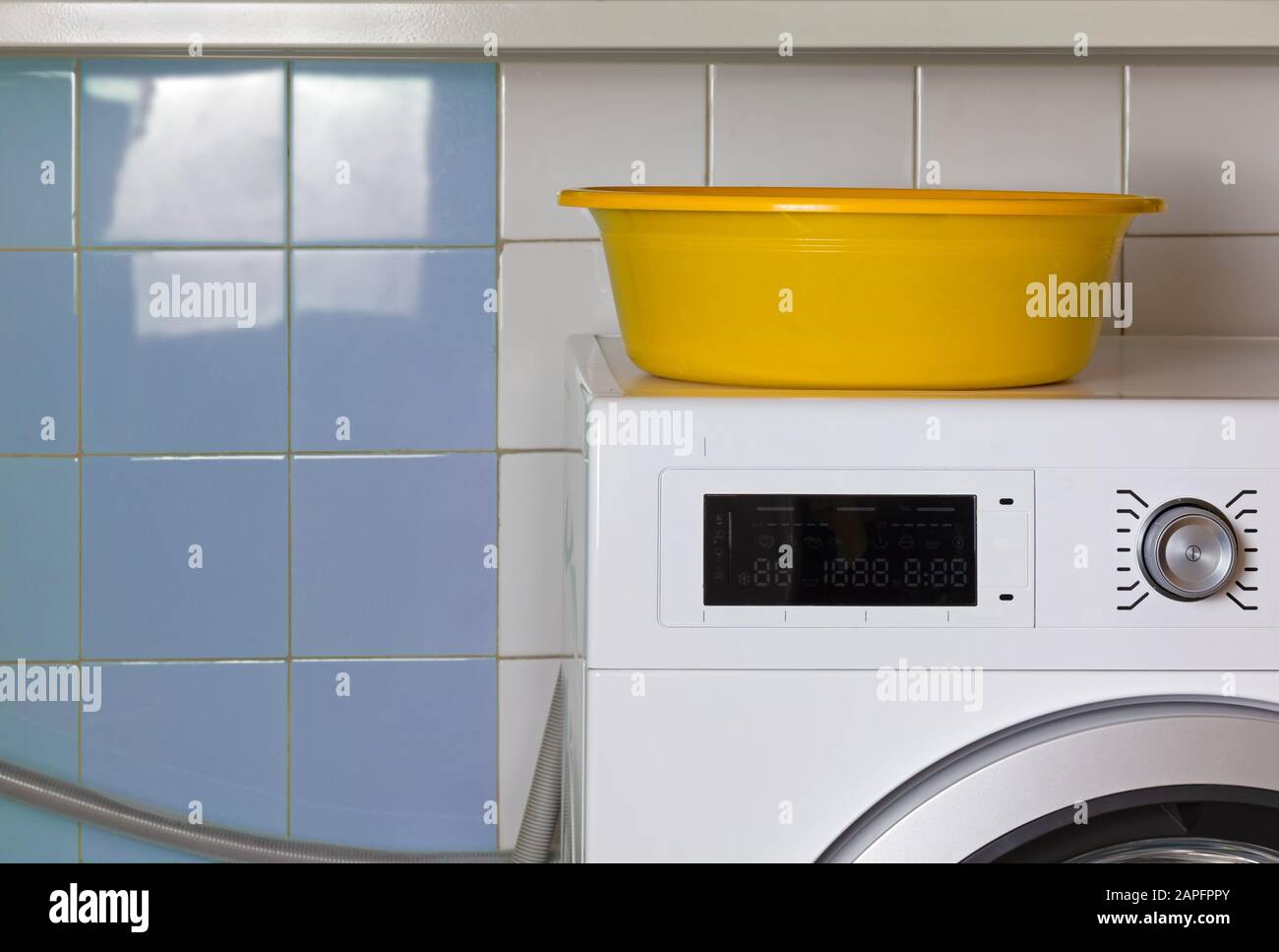 Yellow empty wash bowl on the top of a washing machine in a laundry
