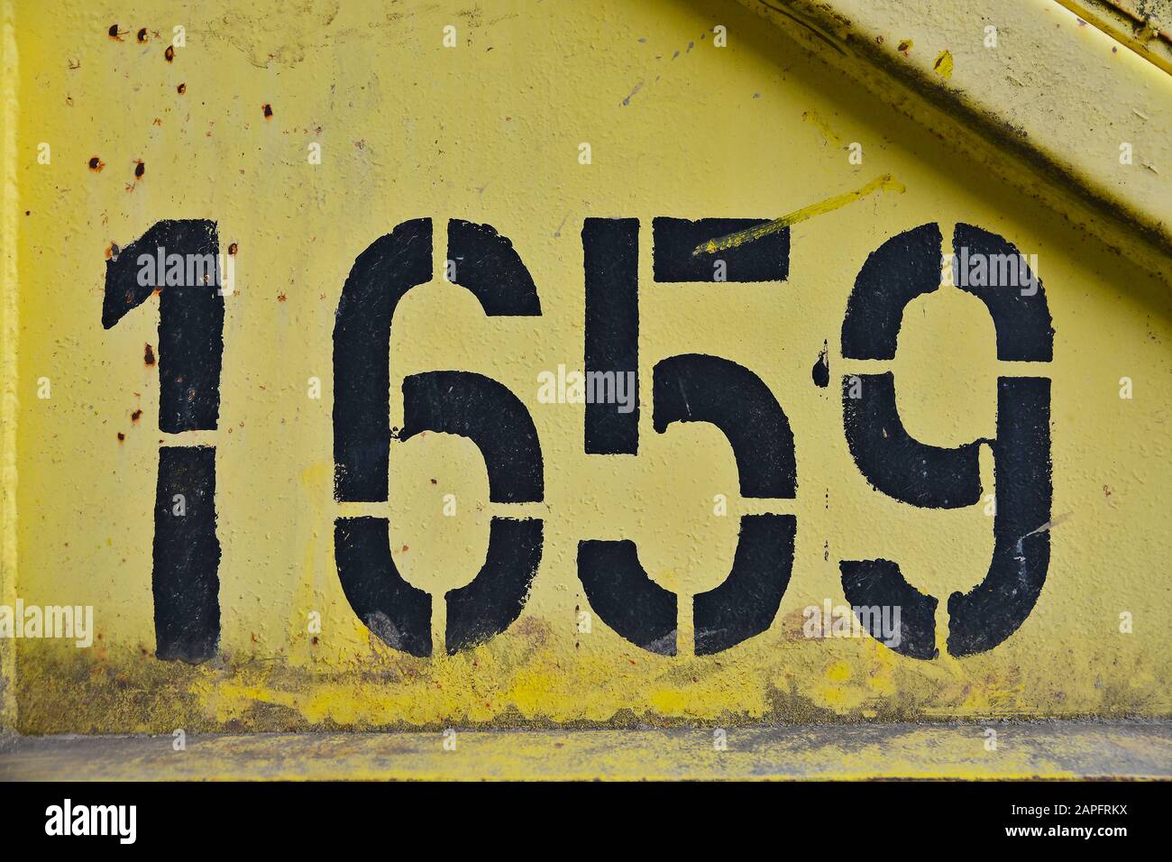Black colored number one thousand six hundred fifty nine (1659) on a yellow rusty metal background. Stock Photo