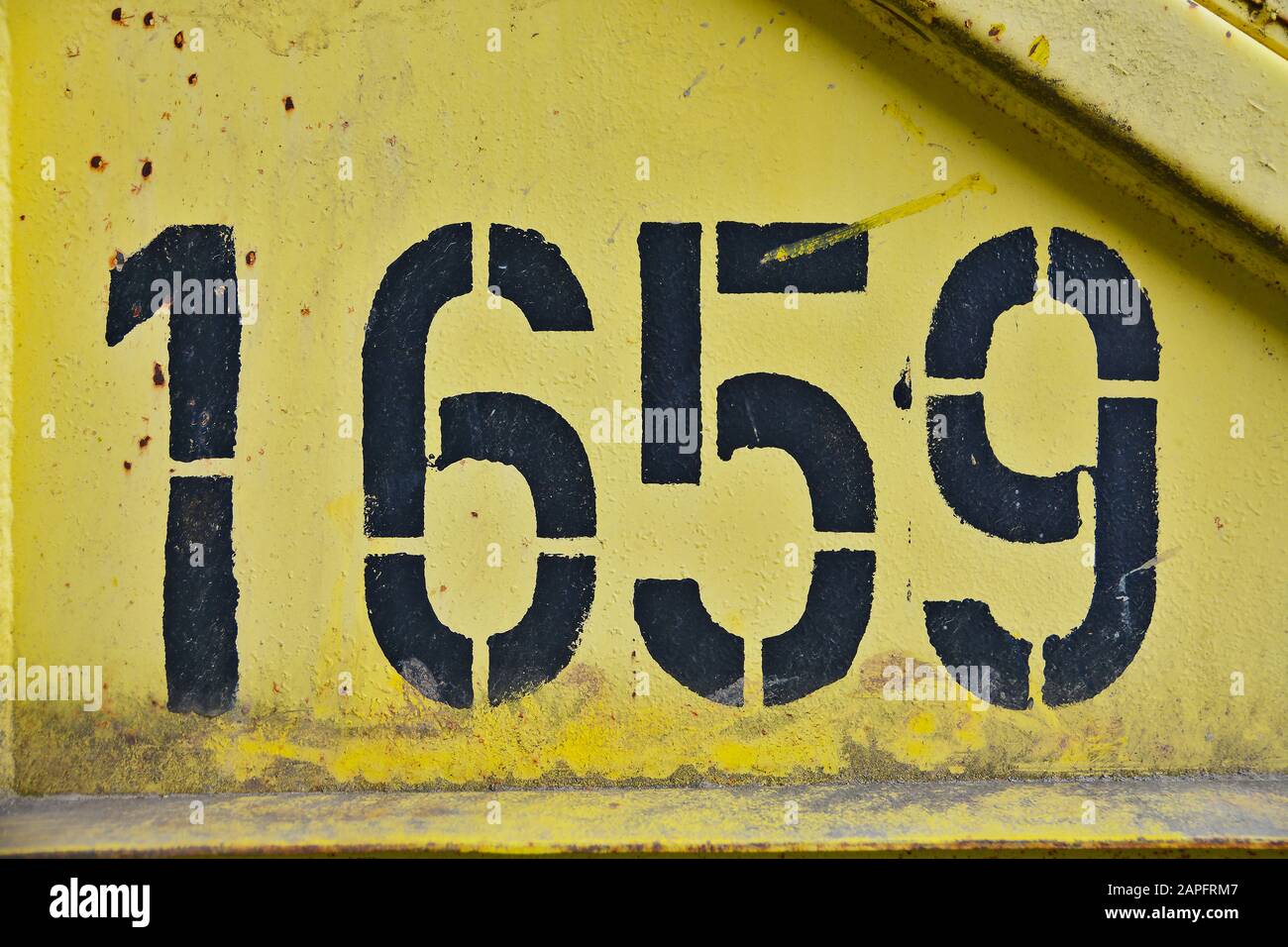 Black colored number one thousand six hundred fifty nine (1659) on a yellow rusty metal background. Stock Photo