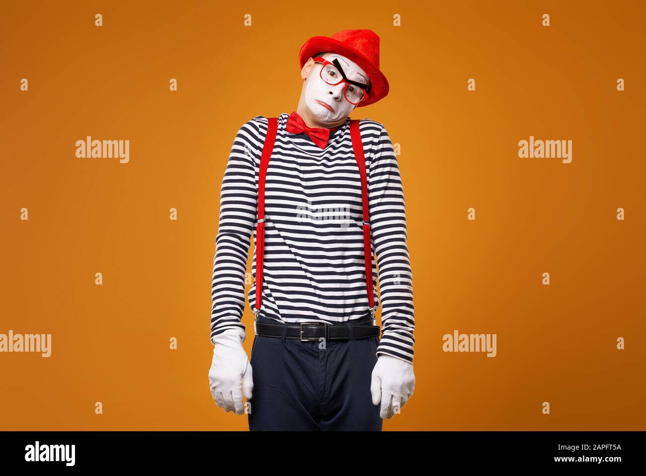 Sad mime in vest and red hat Isolated on orange background Stock Photo