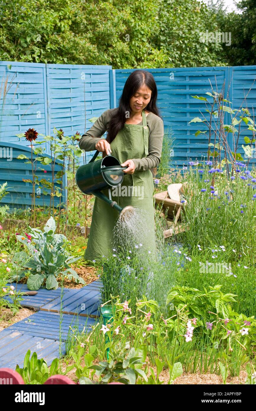 Woman watering an organic flower garden in summer. Stock Photo
