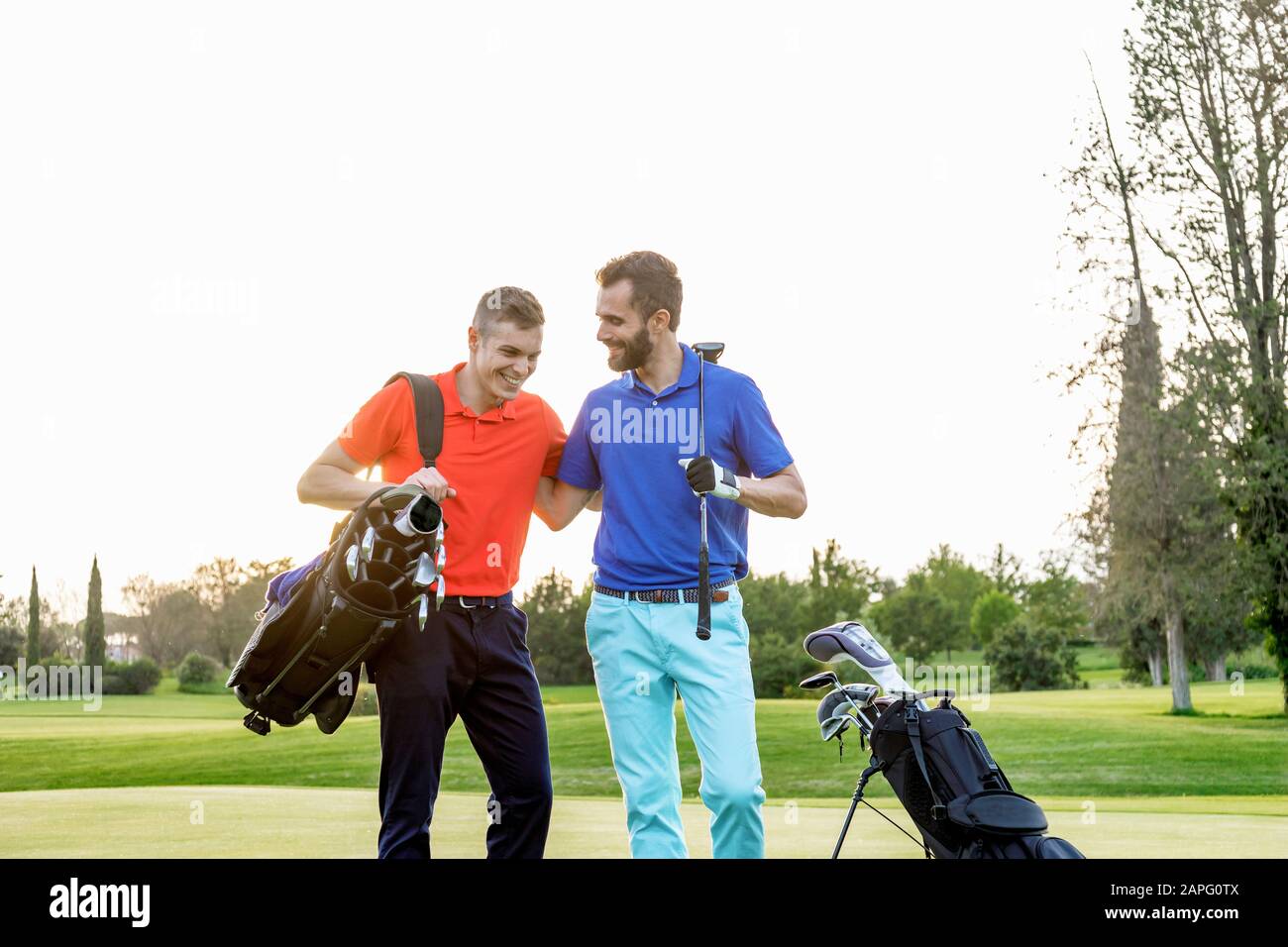 Friends talking and laughing on golf course Stock Photo
