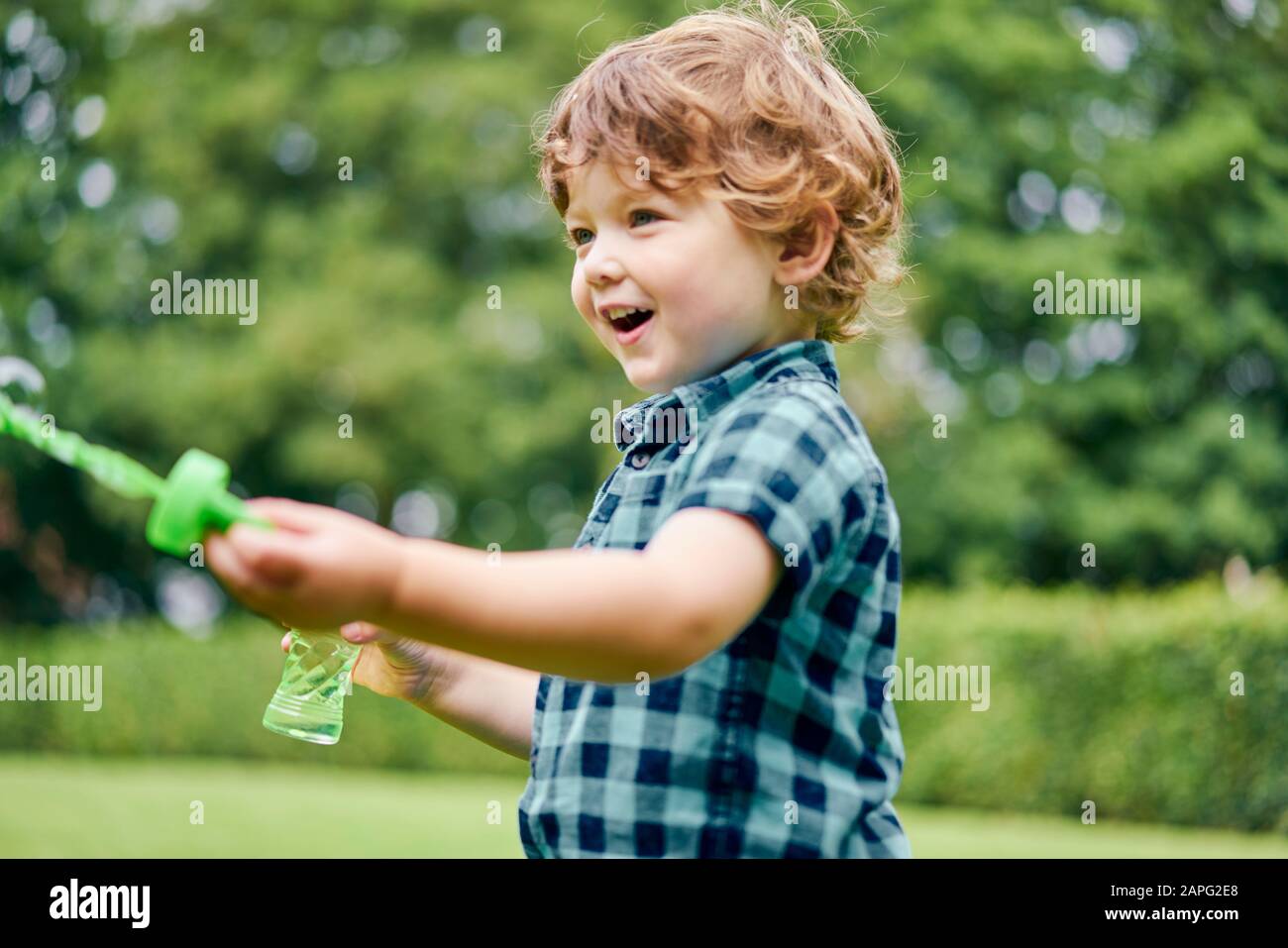Toddler playing with soap bubbles in park Stock Photo