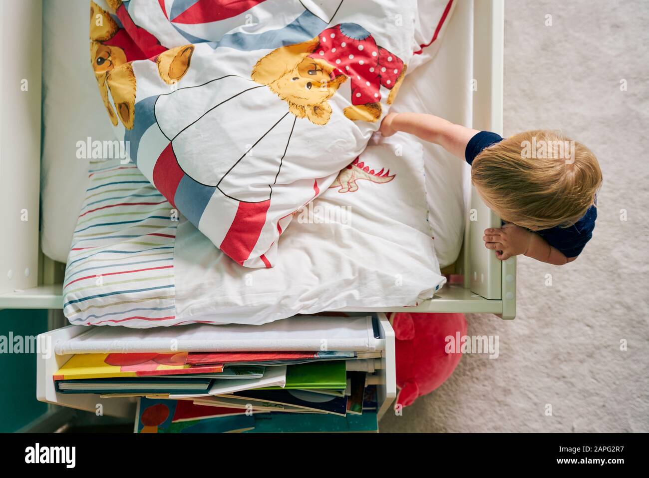 Toddler opening blanket on bed Stock Photo