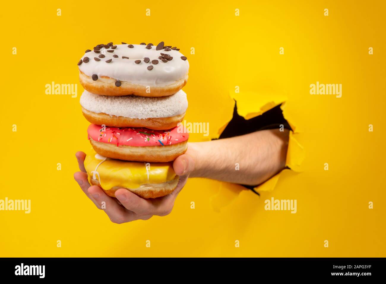 Hand holding a stack of different glazed donuts Stock Photo - Alamy