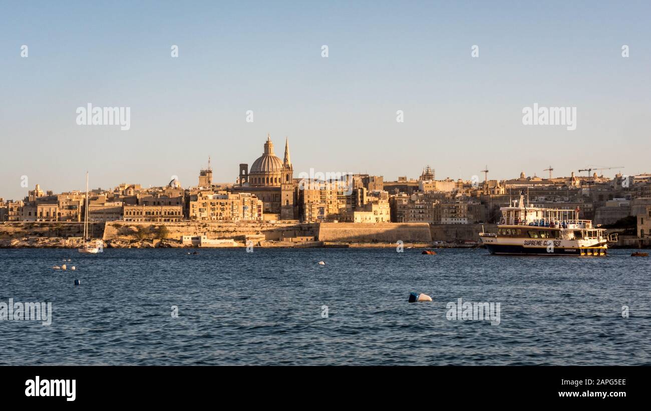 Valletta, Malta. A view of the city skyline of the Maltese capital city, Valletta, with a Supreme Cruises ferry taking tourists Stock Photo