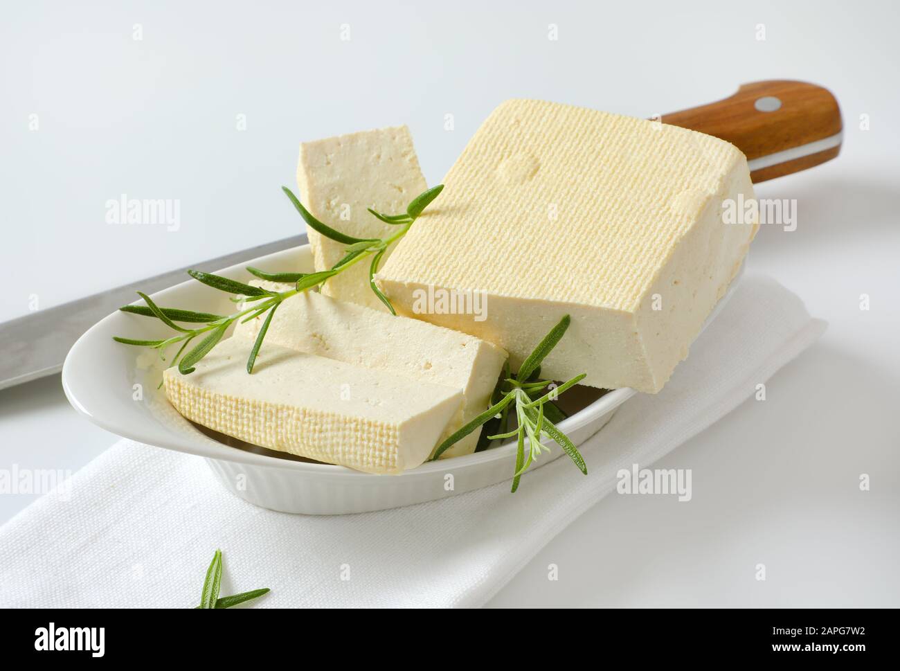 Half a block and slices of firm bean curd (tofu) in white bowl Stock Photo