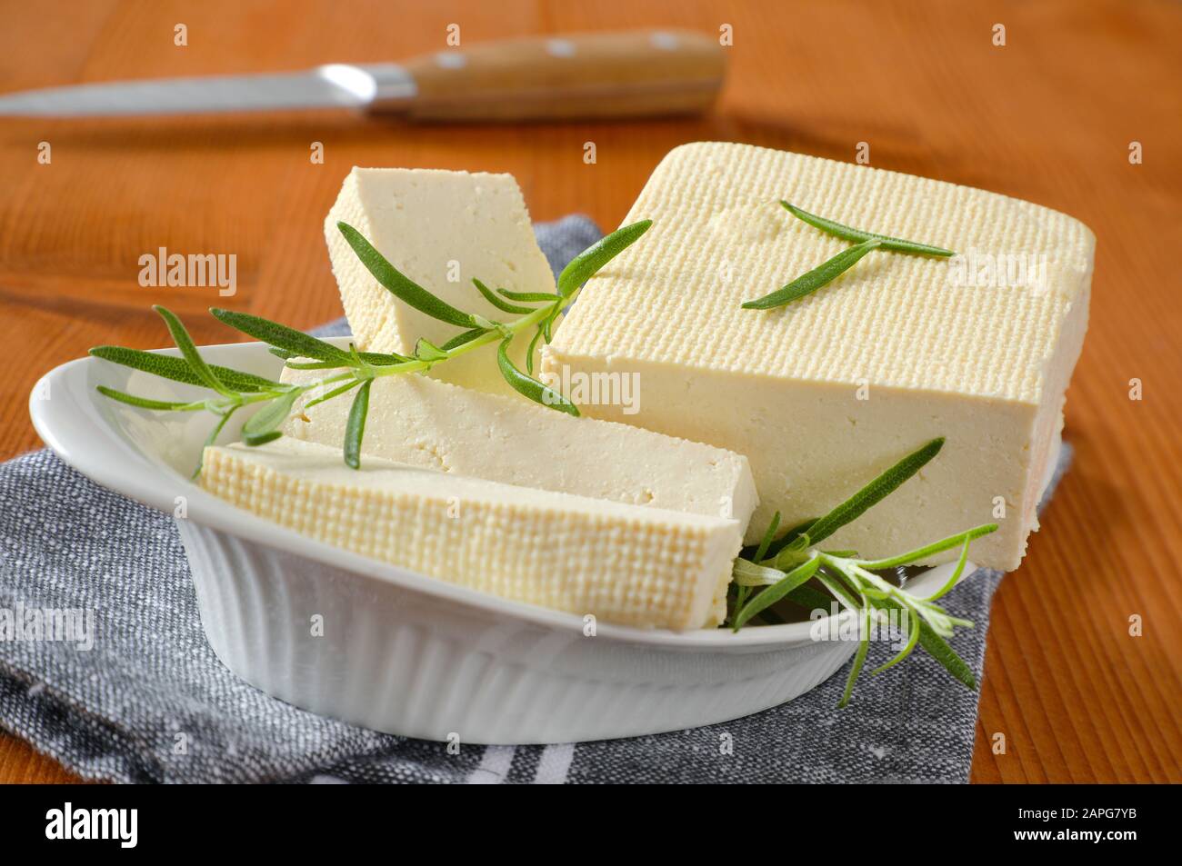 Half a block and slices of firm bean curd (tofu) in white bowl Stock Photo