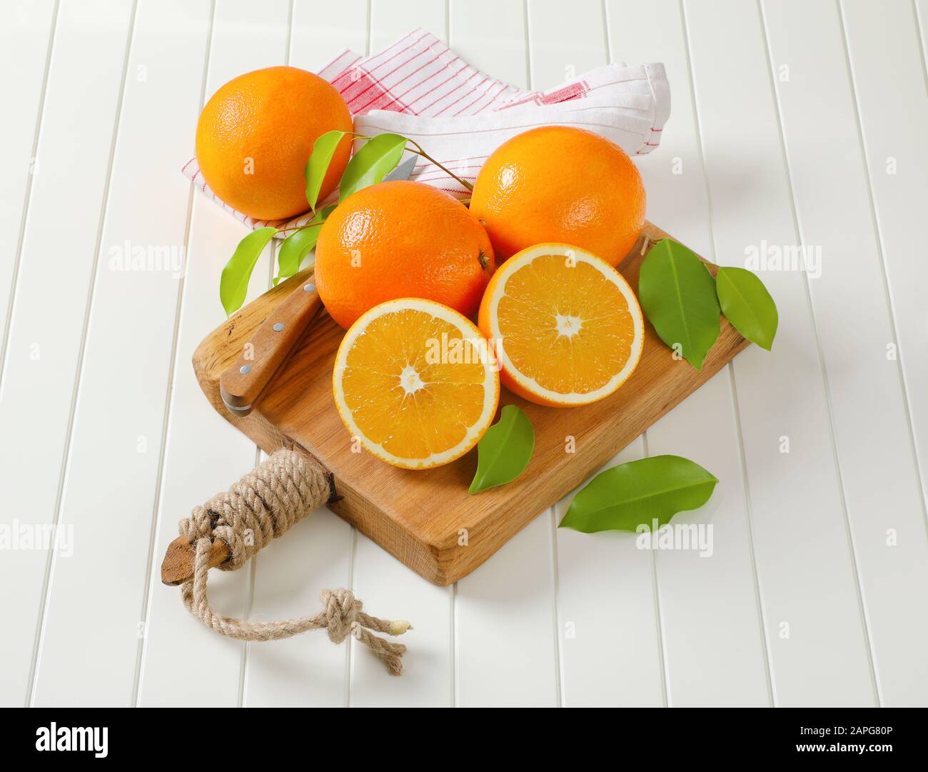 Whole ripe oranges and two halves on cutting board Stock Photo