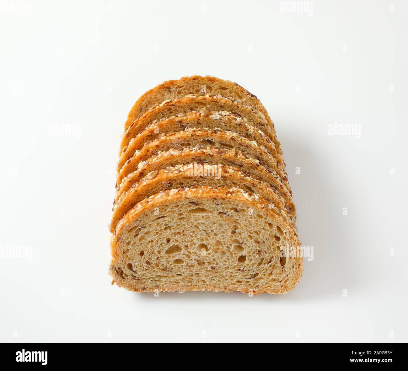 Sliced loaf of whole grain bread, crust topped with rolled oats and seeds (flax, sesame, sunflower) Stock Photo