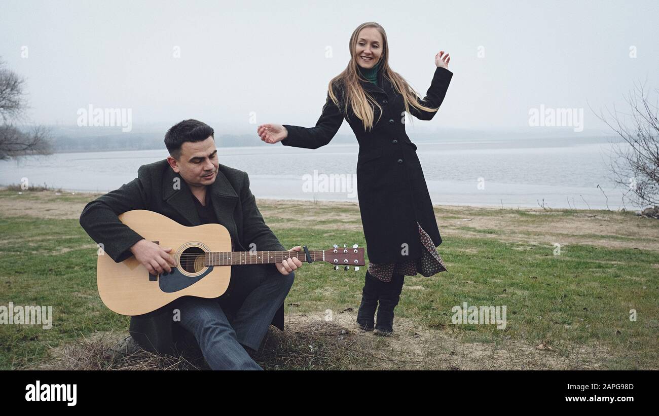 Man playing guitar while his partner is dancing Stock Photo