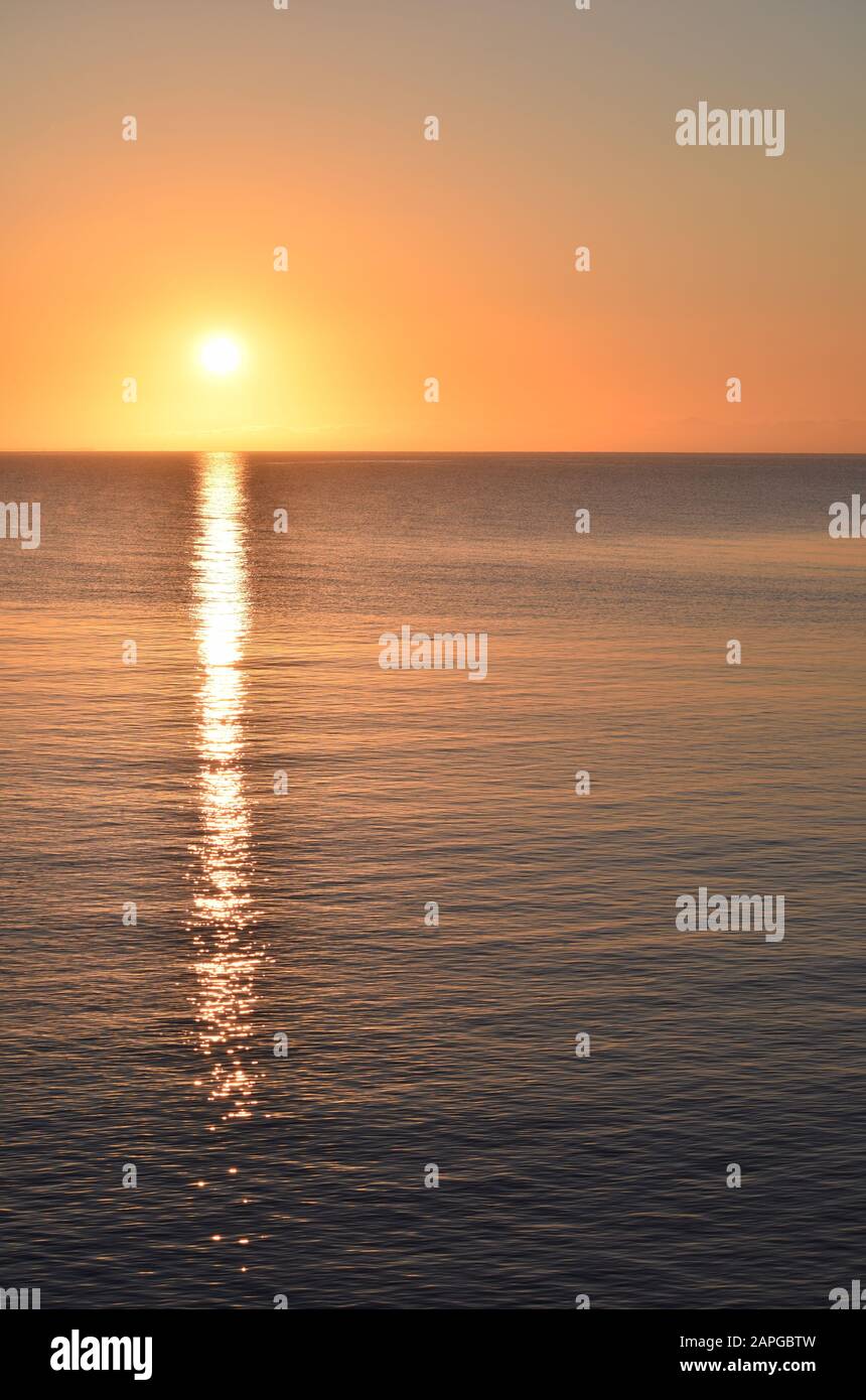 Vertical picture of the sea with the sun reflecting on the water during ...