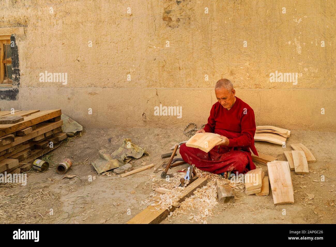 Buddhist monk sitting and making wooden barrel with metal tools at monastery in Kaza, Himachal Pradesh, India. Stock Photo