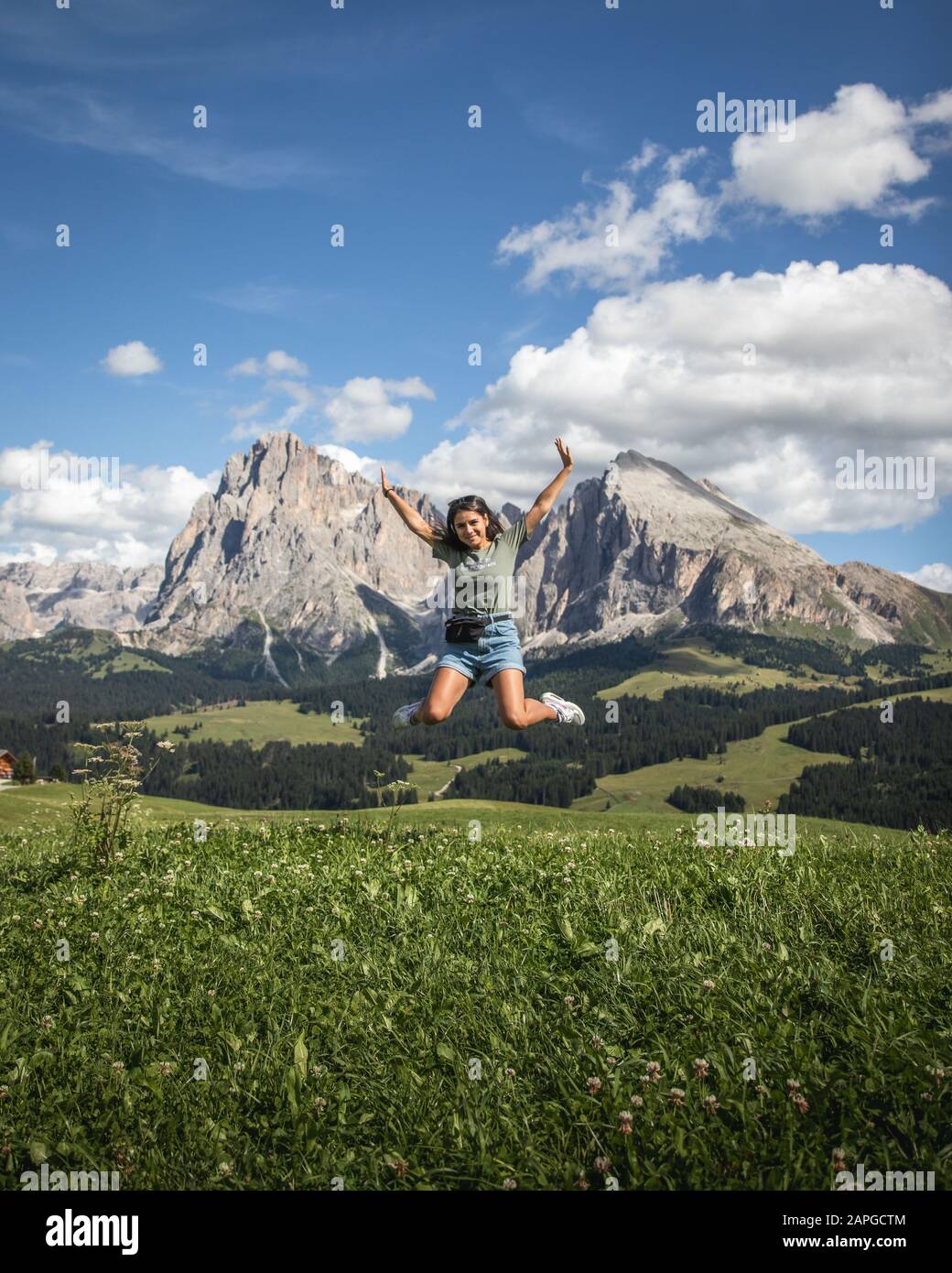 Jump shot of a woman with the Plattkofel mountain as background in  Compatsch Italy Stock Photo