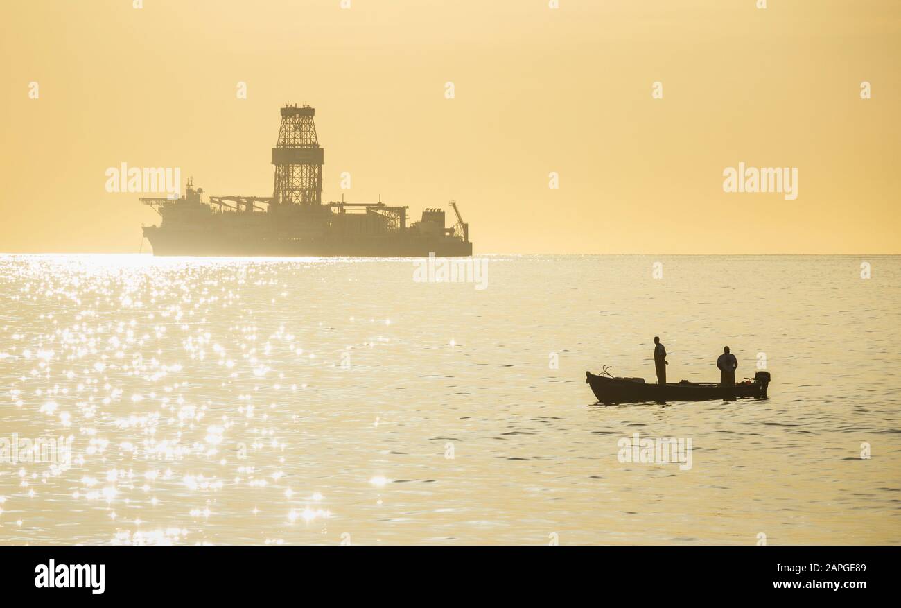 Las Palmas, Gran Canaria, Canary Islands, Spain. 23rd January 2019. A fishing boat sails past a drill ship as the sun rises over the Atlantic ocean on the north coast of Gran Canaria.  Credit: Alan Dawson/Alamy Live News Stock Photo