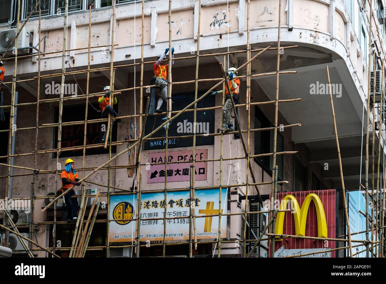Hong Kong, November, 2019: Workers on construction site building bamboo scaffolding on house facade in Hong Kong Stock Photo