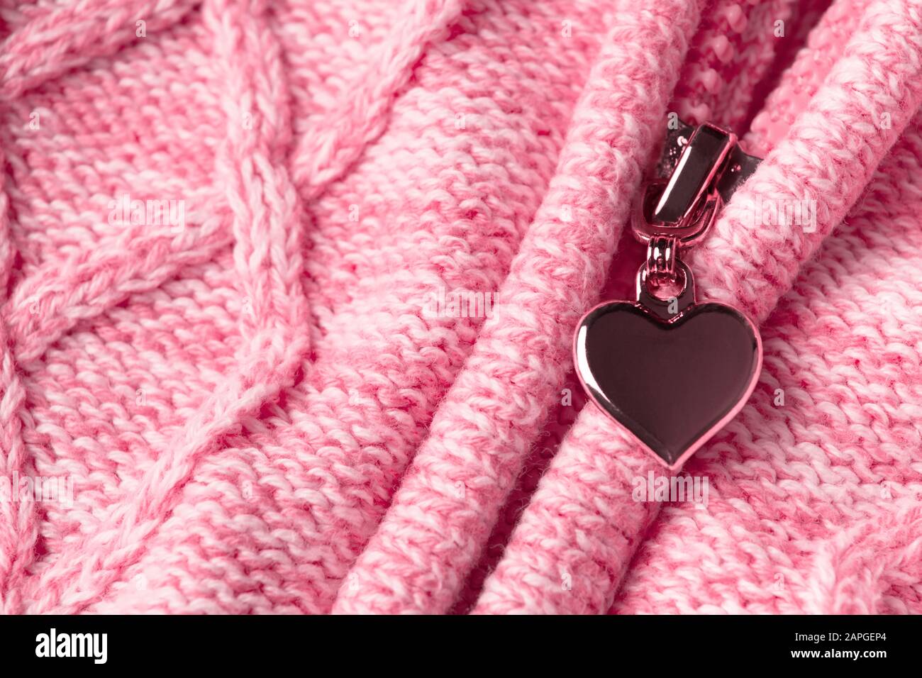 Slider with shape of heart in zipper on textile woolen pink clothes. Valentine's day material background. Love concept. Abstract love sign Stock Photo