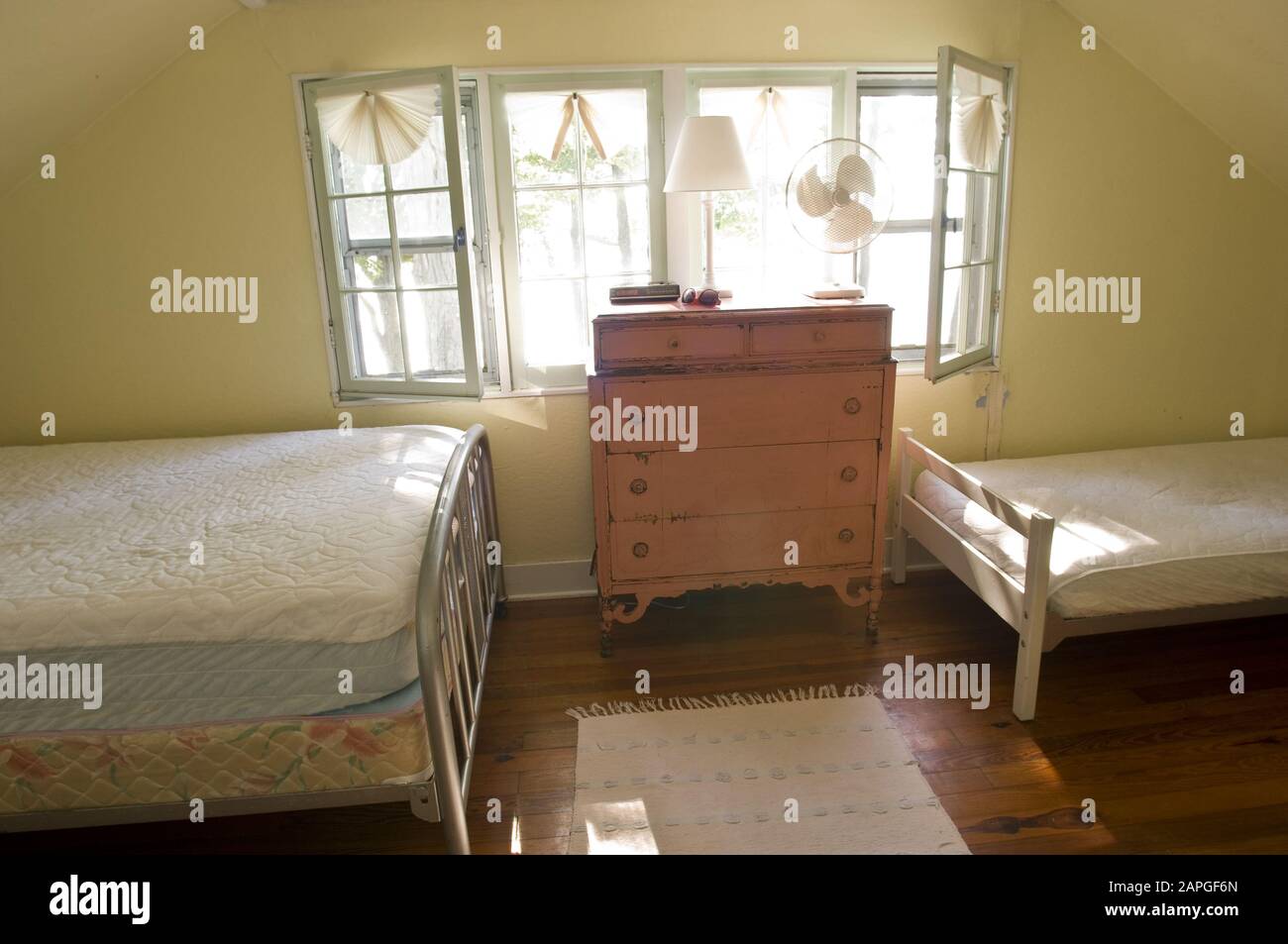 Old fashioned bedroom with two beds and a cupboard under the sunlight from the windows Stock