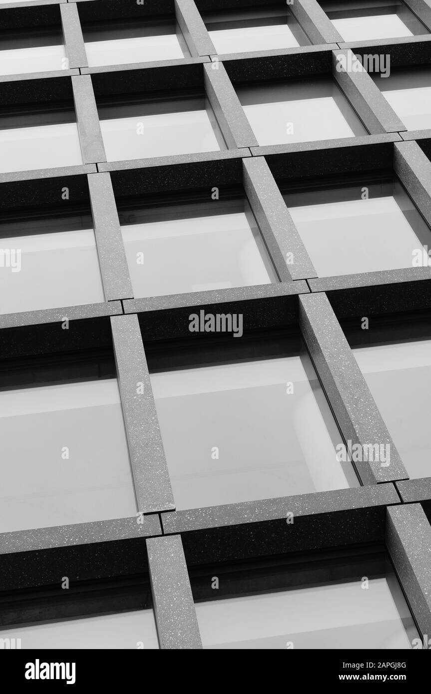 Vertical grayscale shot of an office building with windows Stock Photo