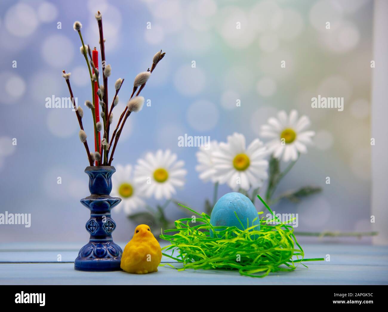 Easter card. A painted egg in a nest, willow branches and a candle ...