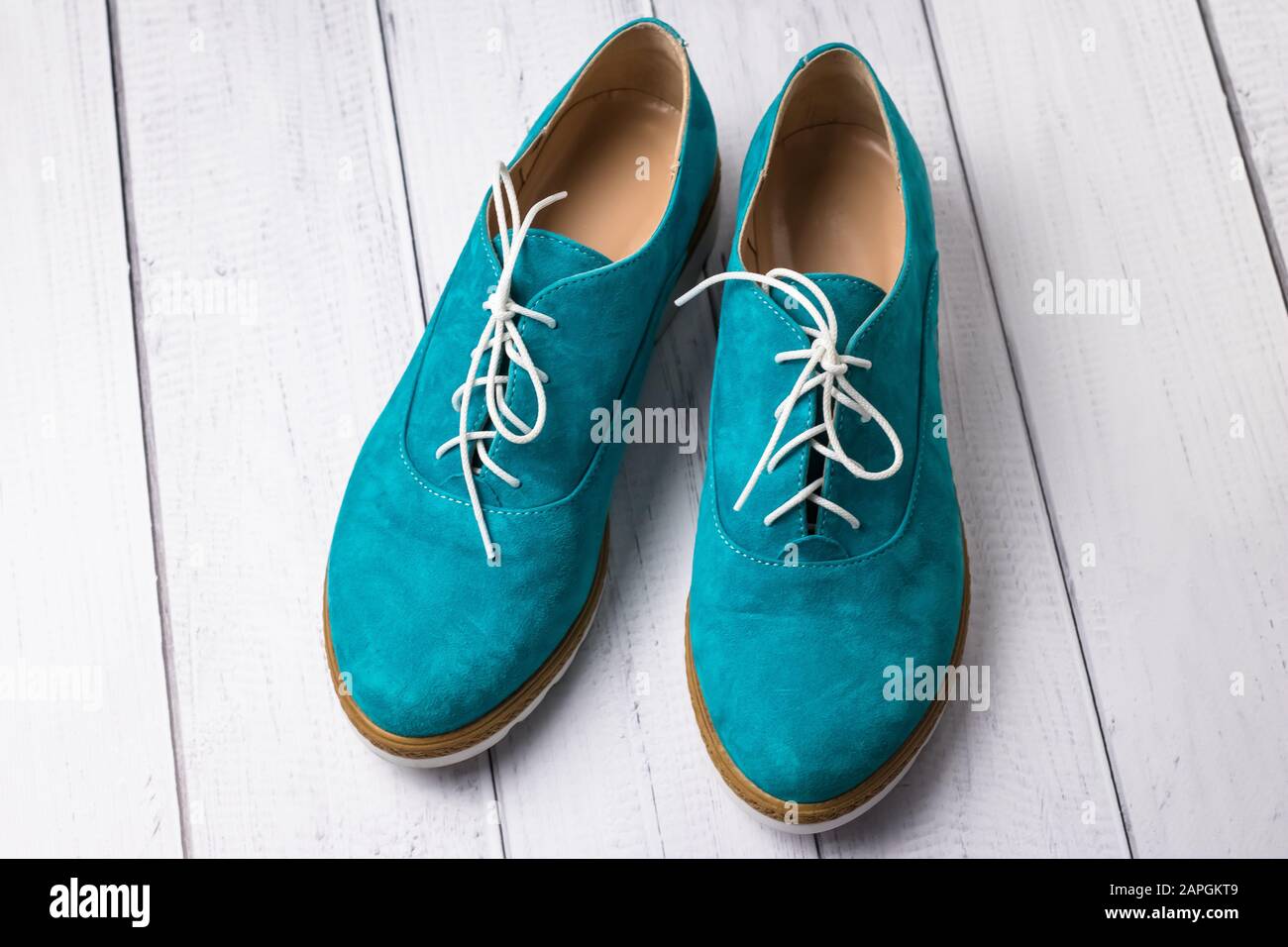 Pair of green casual suede shoes with laces on wooden background. Turquoise women's oxfords, oxford shoe Stock Photo