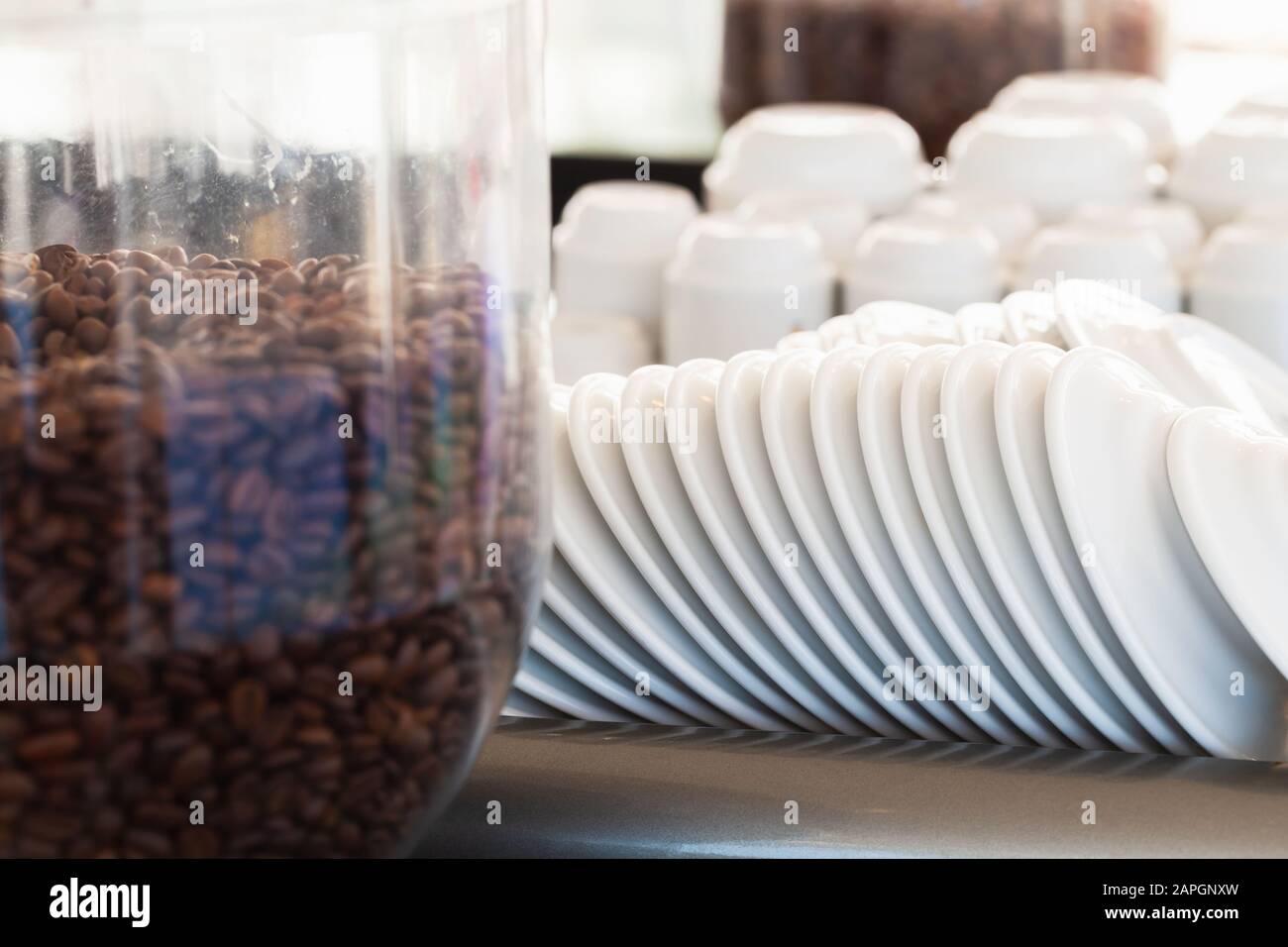 White ceramic saucers and small espresso cups stacked on the upper shelf of professional coffee machine, close-up photo with selective focus Stock Photo