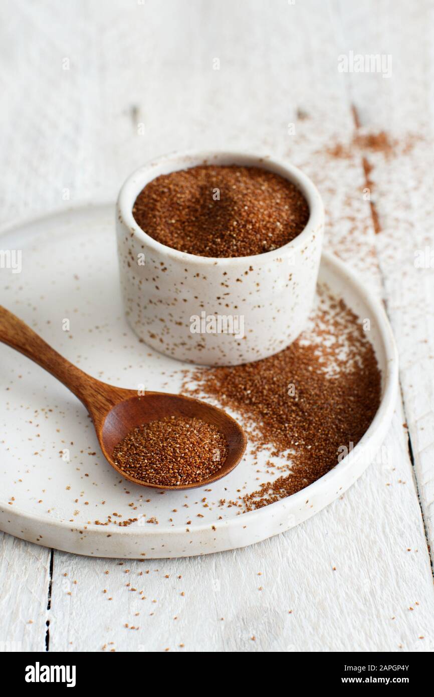 Uncooked teff grain in a bowl with a wooden spoon close up Stock Photo