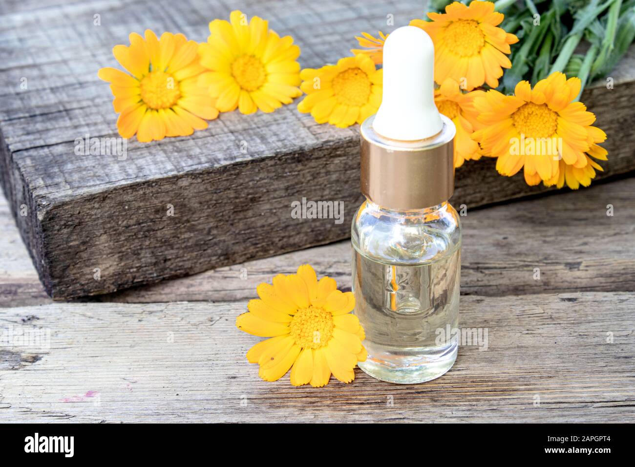 Bottle of calendula oil on a wooden background. Extract of tincture of ...