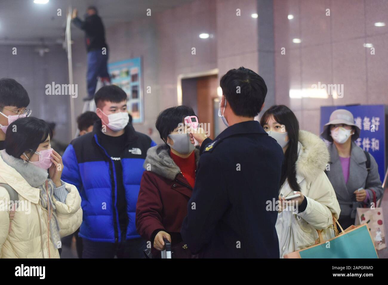 Chinese workers check body temperatures of the passengers wearing face masks for the prevention of the new coronavirus at Hangzhou Railway Station in Stock Photo