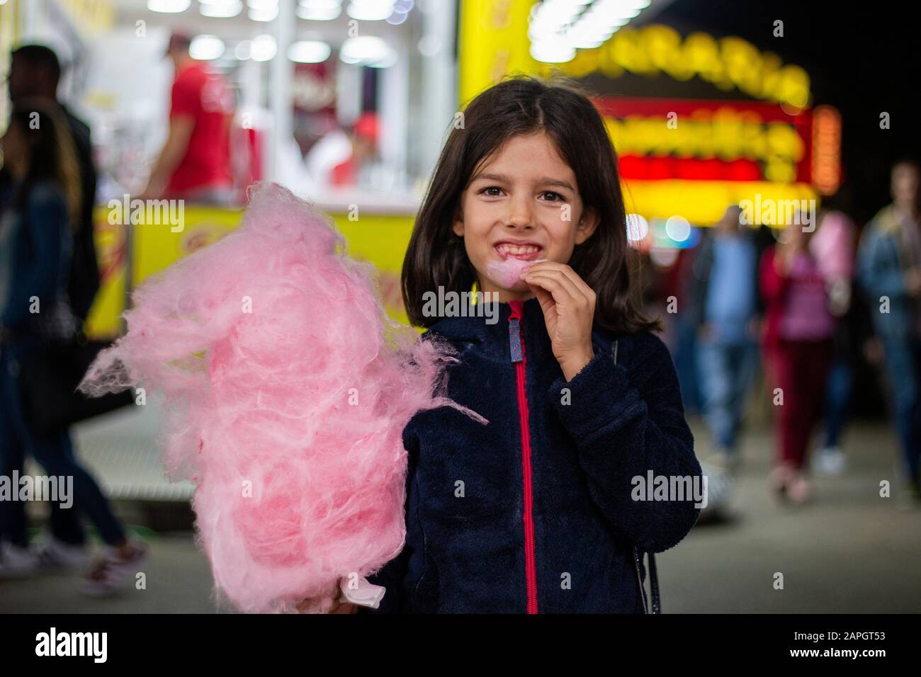Cute girl eating a big ball of cotton candy on a amusement park Stock Photo Alamy