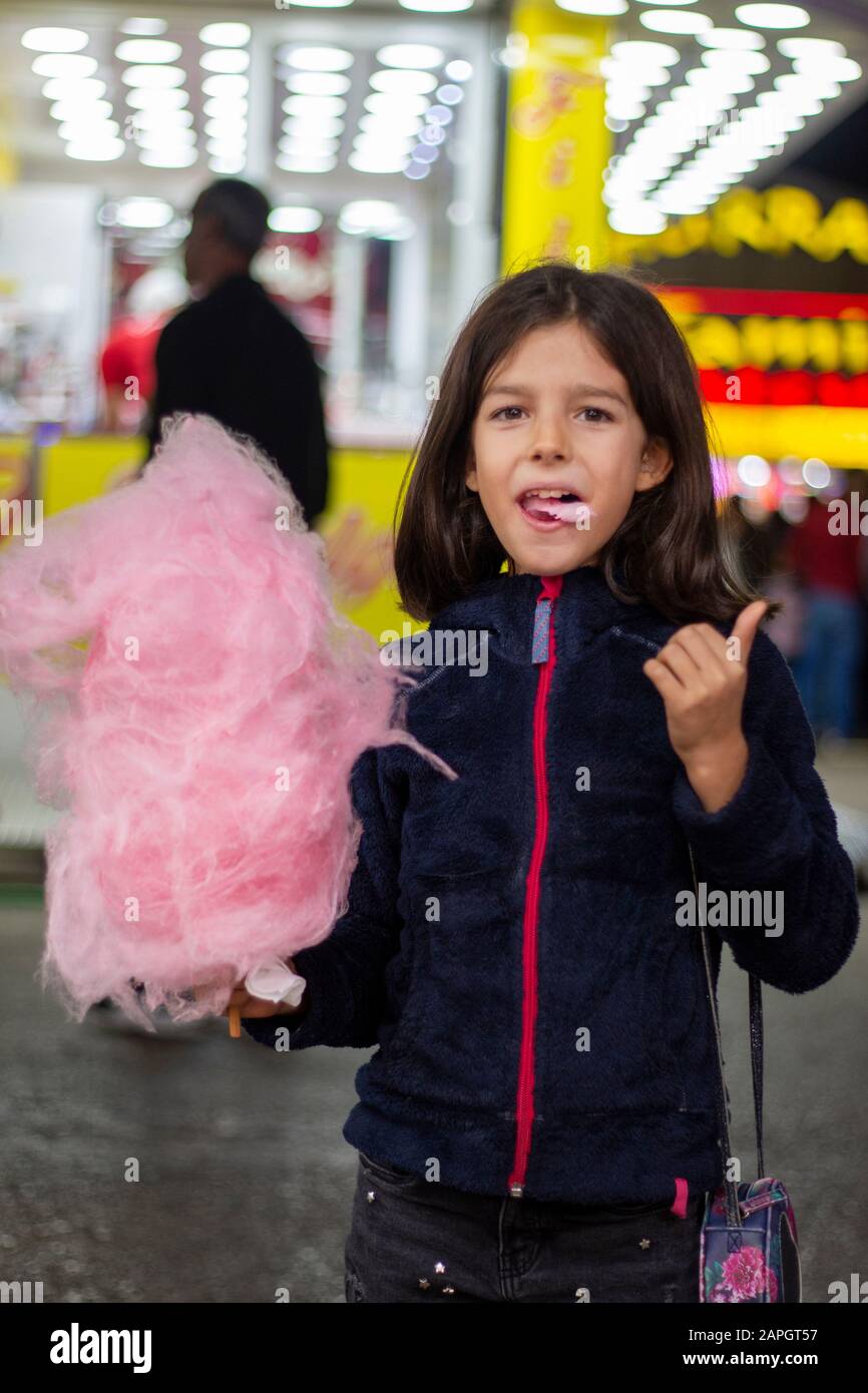 Cute girl eating a big ball of cotton candy on a amusement park Stock Photo Alamy