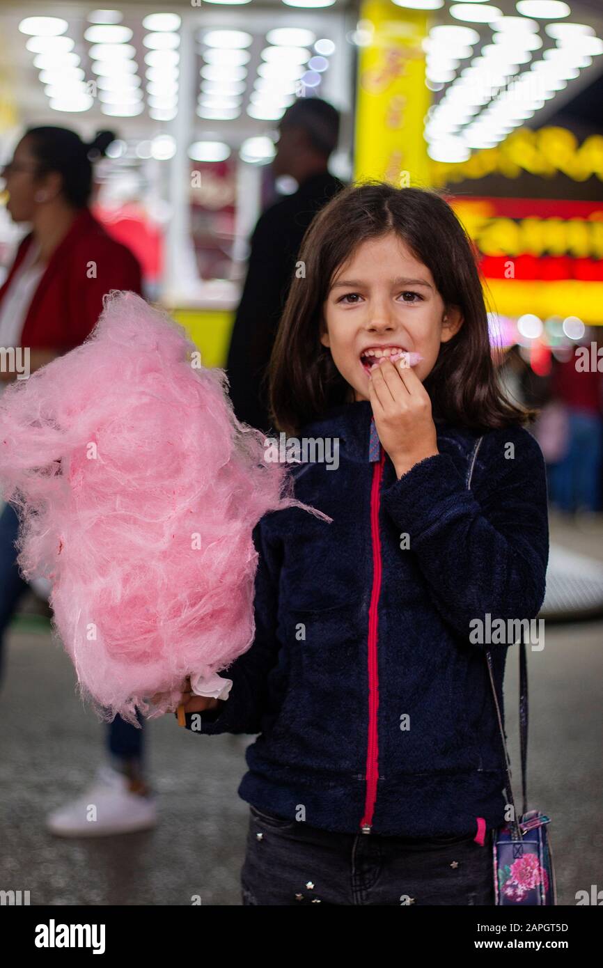 Cute girl eating a big ball of cotton candy on a amusement park Stock Photo Alamy