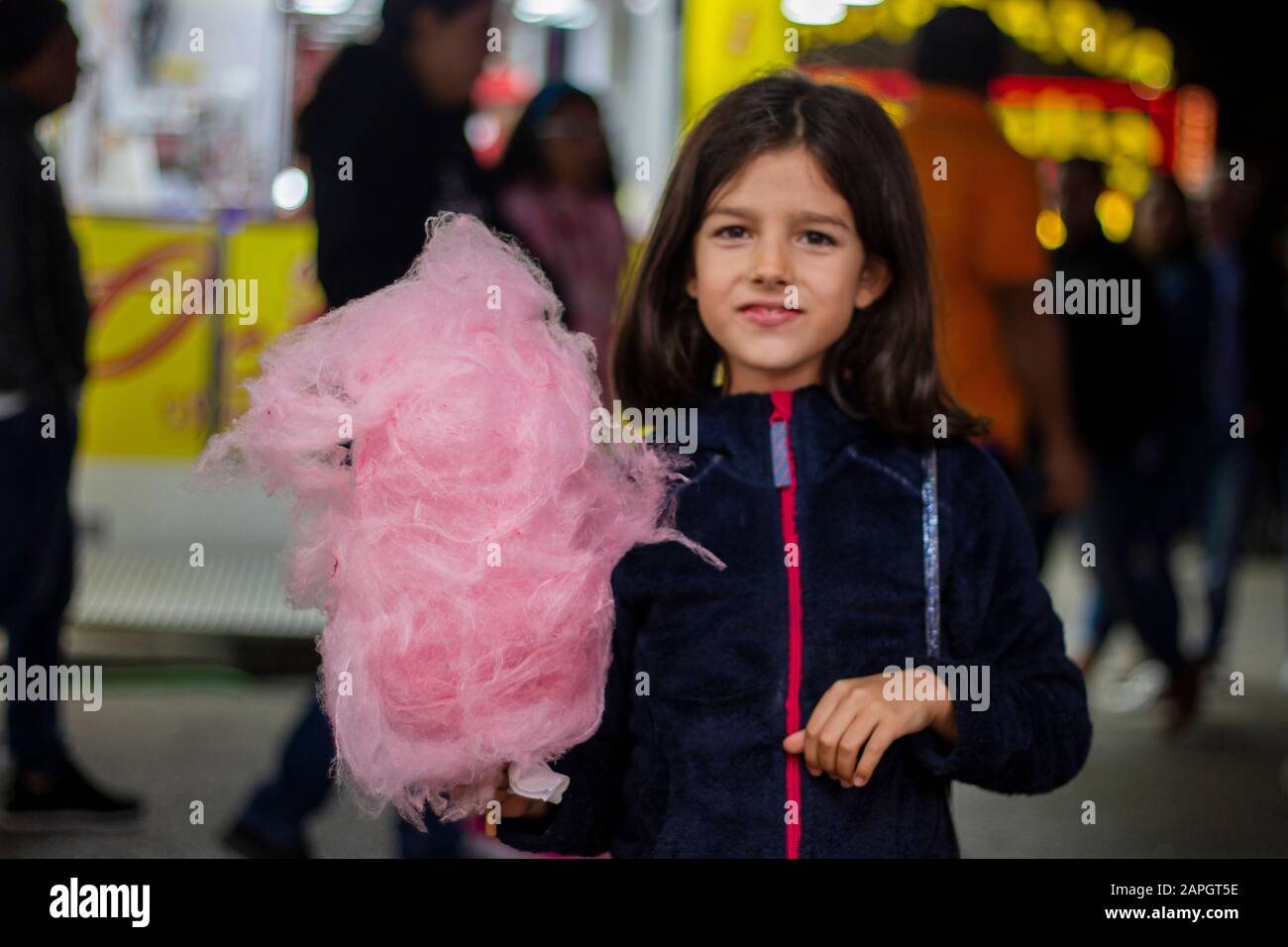 Cute girl eating a big ball of cotton candy on a amusement park Stock Photo Alamy