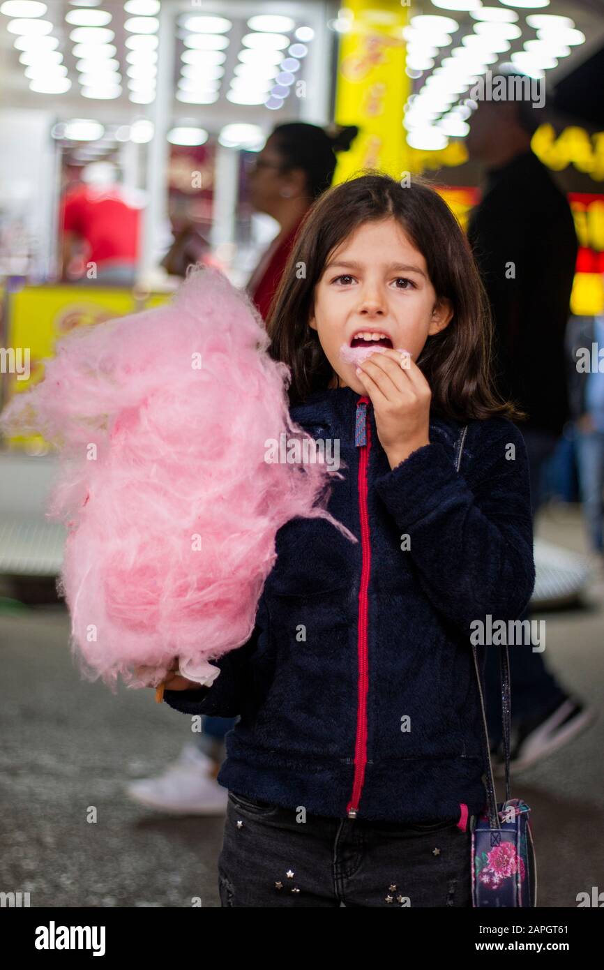Cute girl eating a big ball of cotton candy on a amusement park Stock Photo Alamy