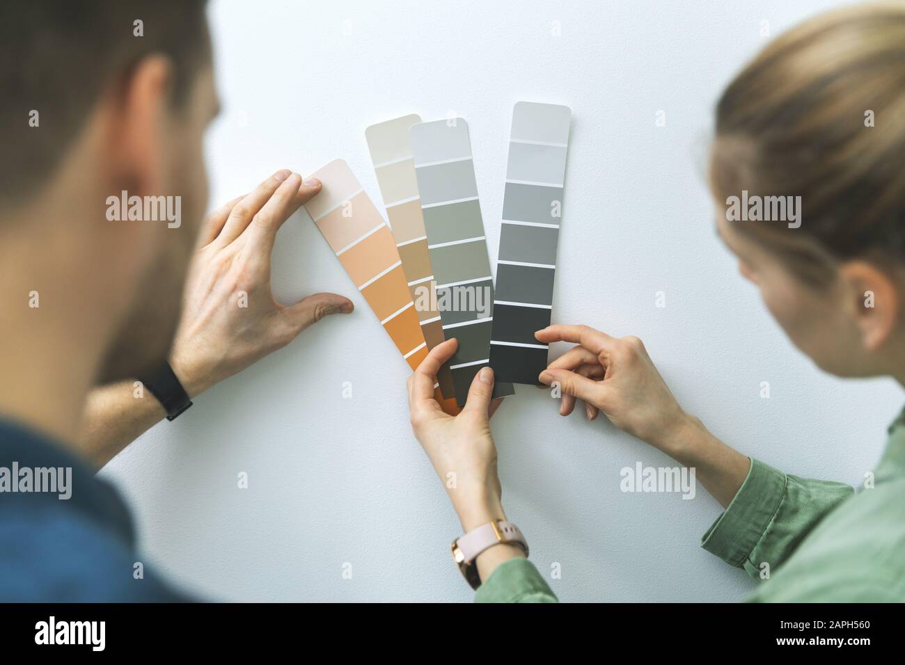 young couple choosing paint color from samples for new home interior design Stock Photo