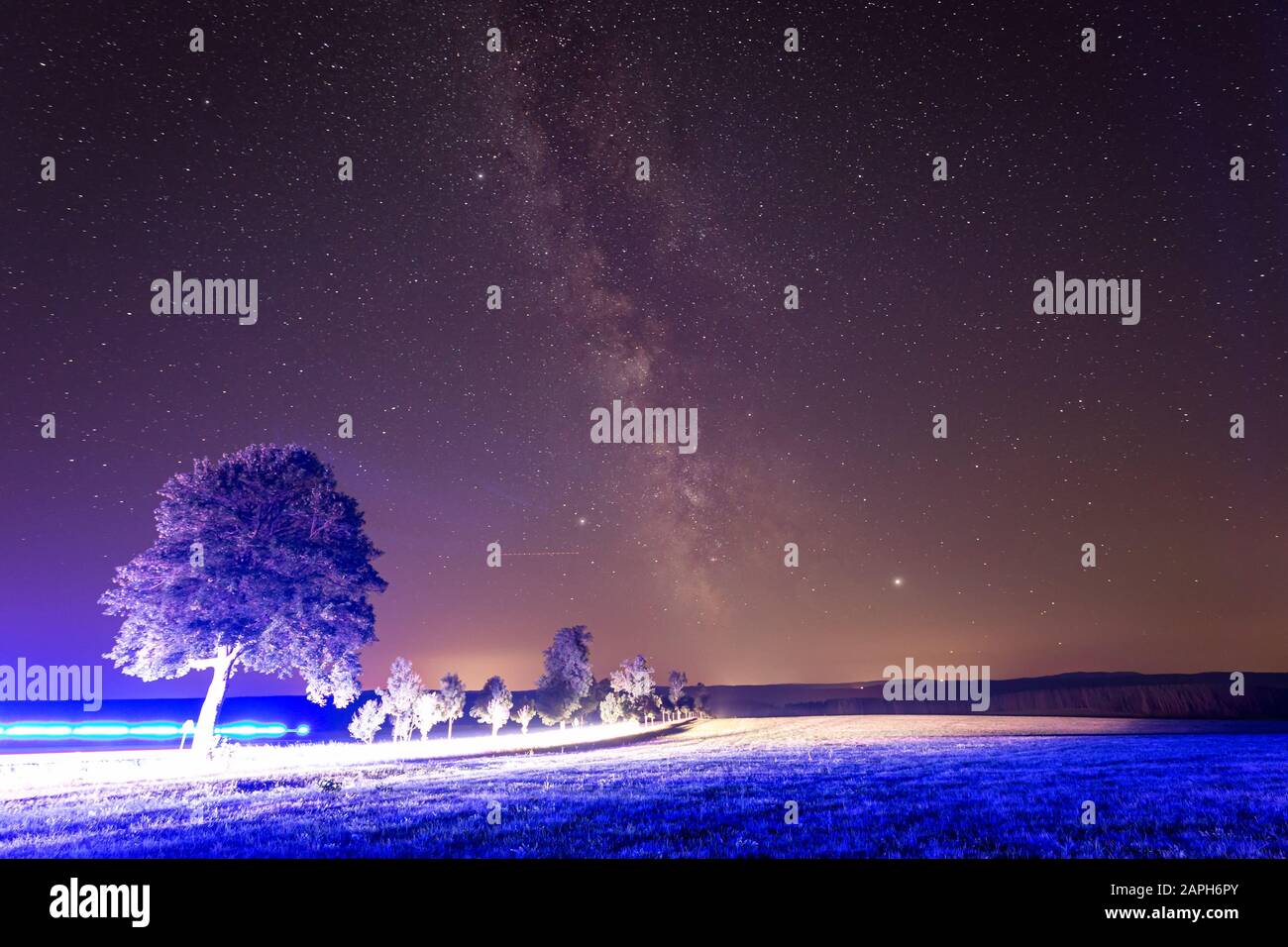 Milky way and starry sky with illumination from the road. Blue street light. Stock Photo