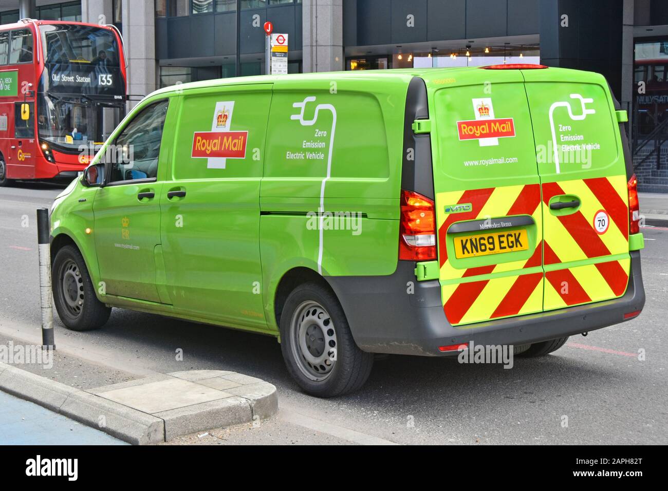 View of green coloured Royal Mail Zero Emissions Electric post delivery van with graphics on one side & back with standard red opposite side London UK Stock Photo