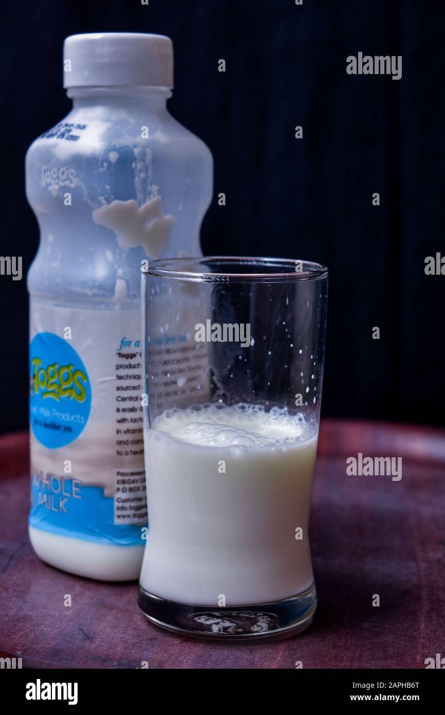 Kiambu/Kenya - January 23rd 2020: a half filled tumbler with  goats milk next to a container of milk that was processed by kibidav farm in Kenya. Stock Photo