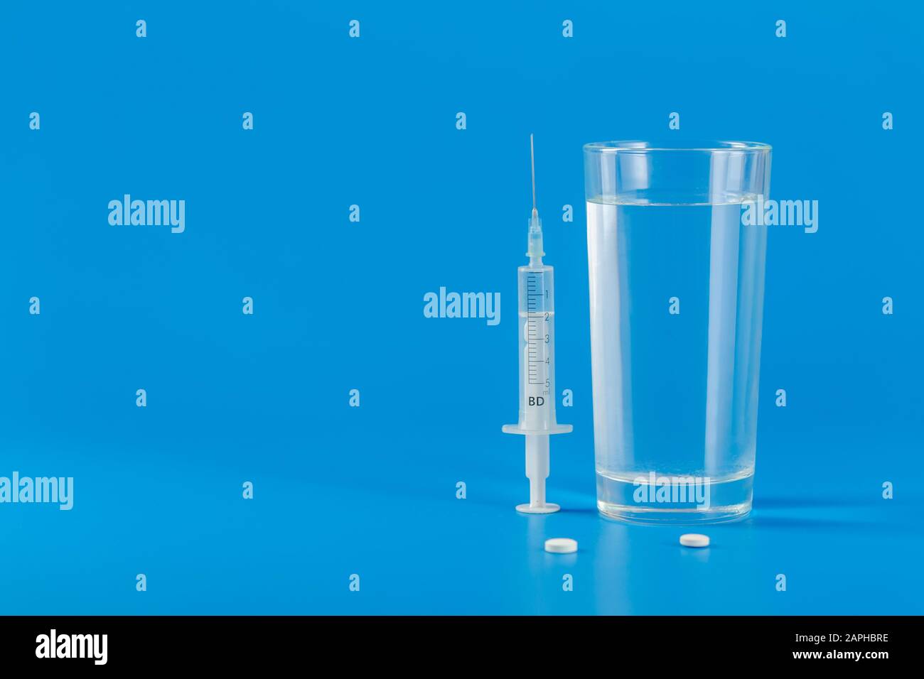 Glass with water and various pills isolated on blue background with copy space Stock Photo