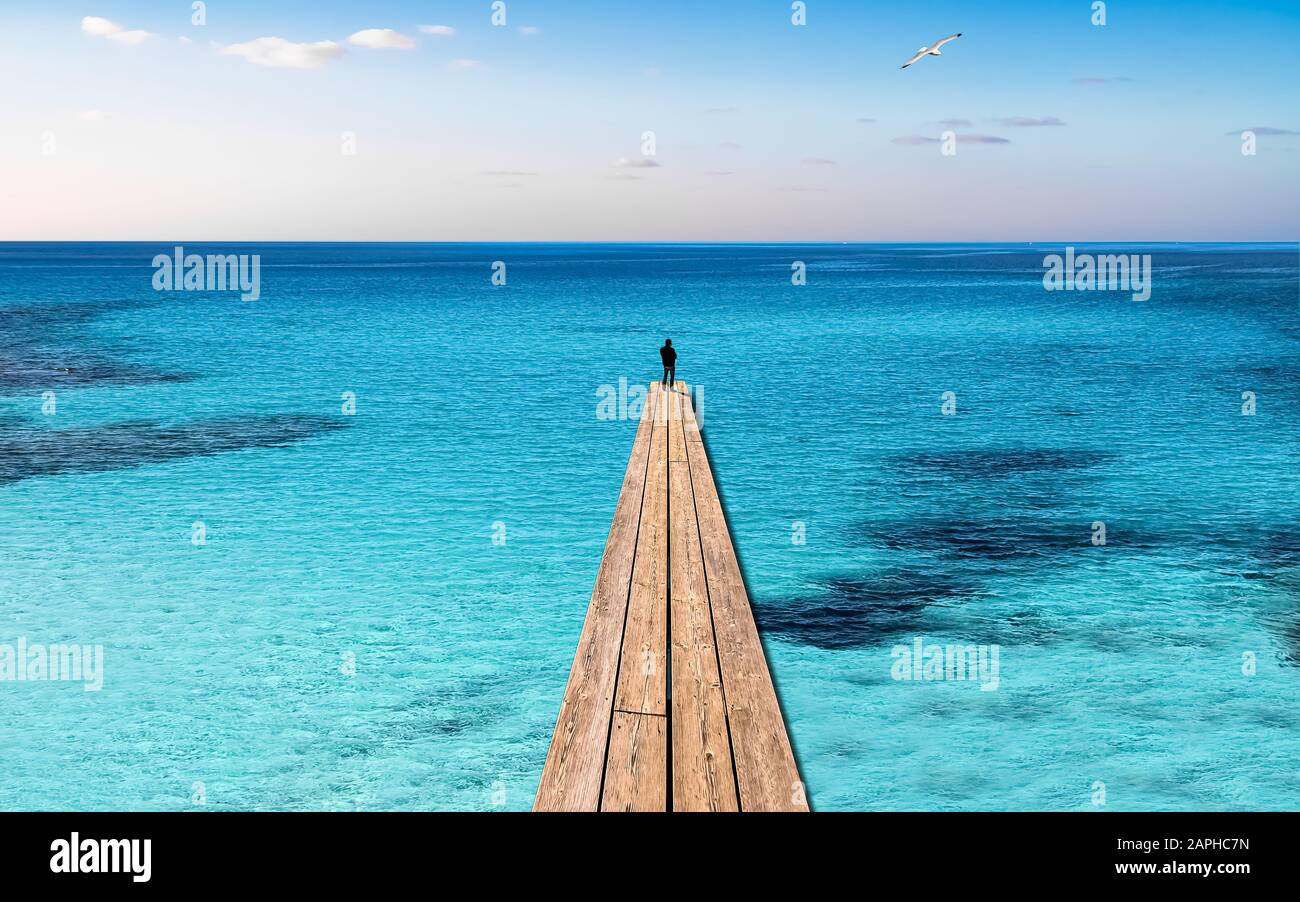 Silhouette of One Single Person standing on a Landing Stage in a Turquoise Ocean Stock Photo