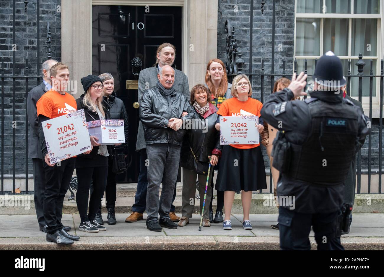 10 Downing Street, London, UK. 23rd January 2020. Mother of Amy Winehouse, an MS sufferer, (holding walking stick) with MS Society staff hands a petition of 21,042 signatures saying unfair PIP assessments must change into 10 Downing Street asking PM Boris Johnson to change the benefits system and amend the process for claiming PIPs (Personal Independence Payments). Credit: Malcolm Park/Alamy Live News. Stock Photo