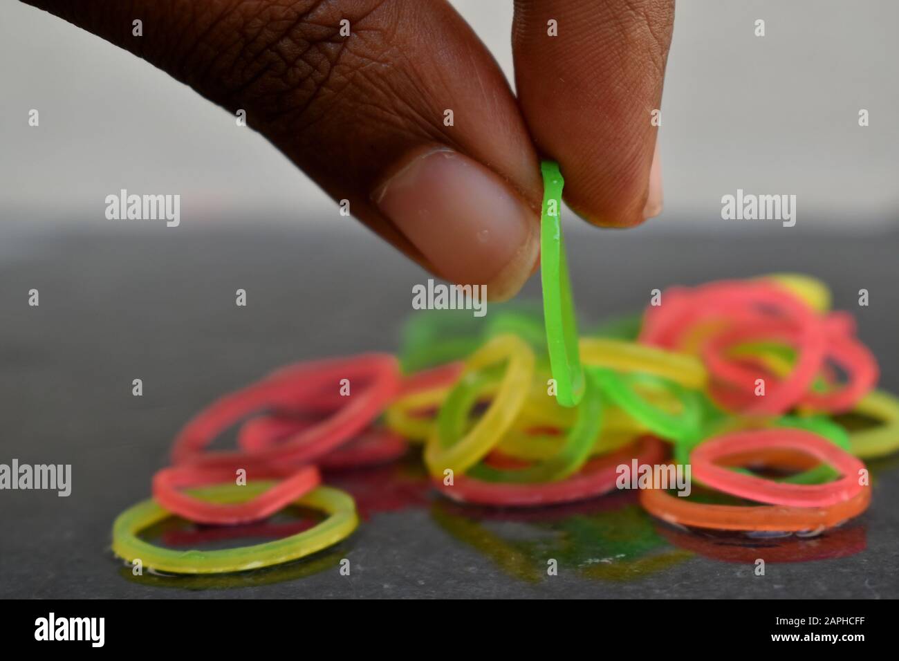 Multi color rubber bands picked by hand. Rubber bands and fingers. Rubber bands thrown from hand. Stock Photo